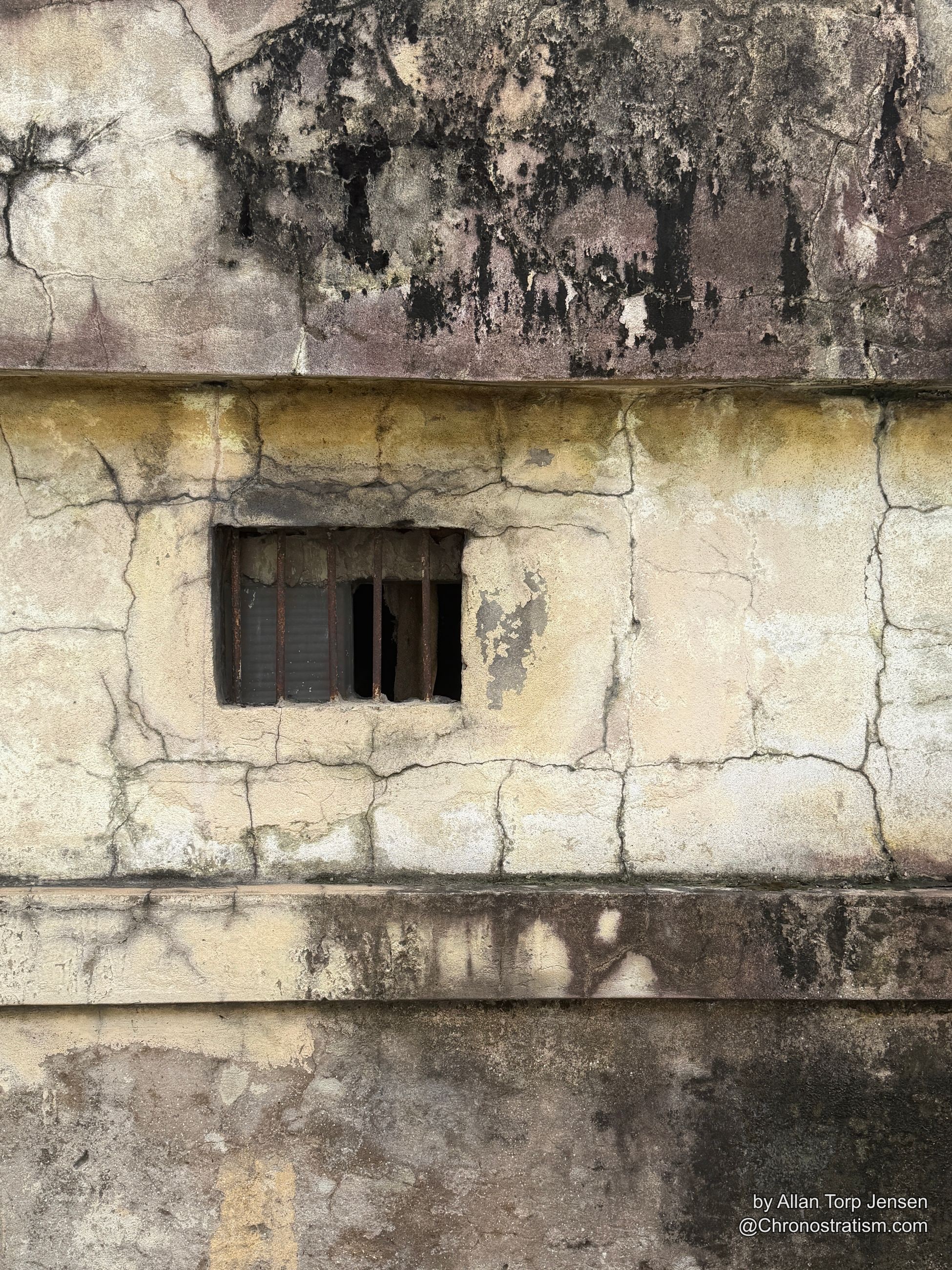 Black soot and mold patches spread either side of a vent on a cracked concrete wall.