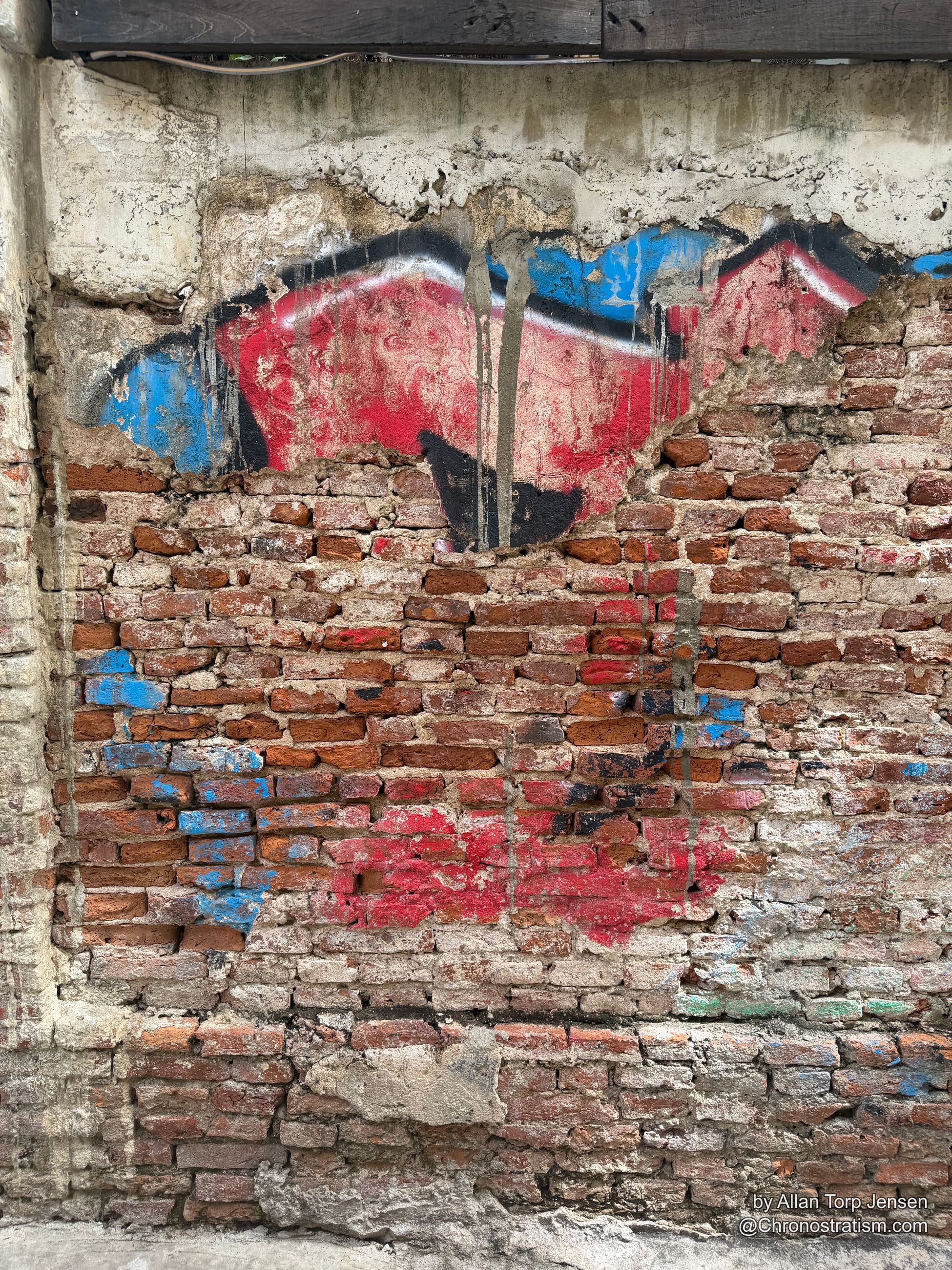 Blue paint outlines the stencilled figure where plaster has fallen away to brick.
