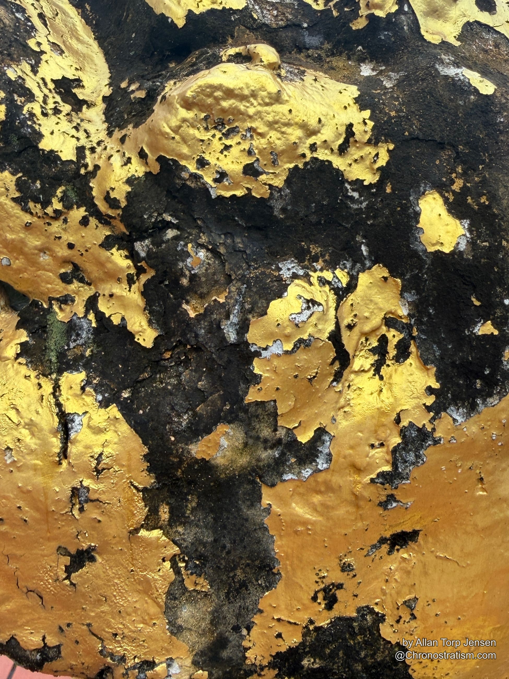 Close-up of the guardian statue’s snout and head, gold leaf patchy beneath heavy soot.