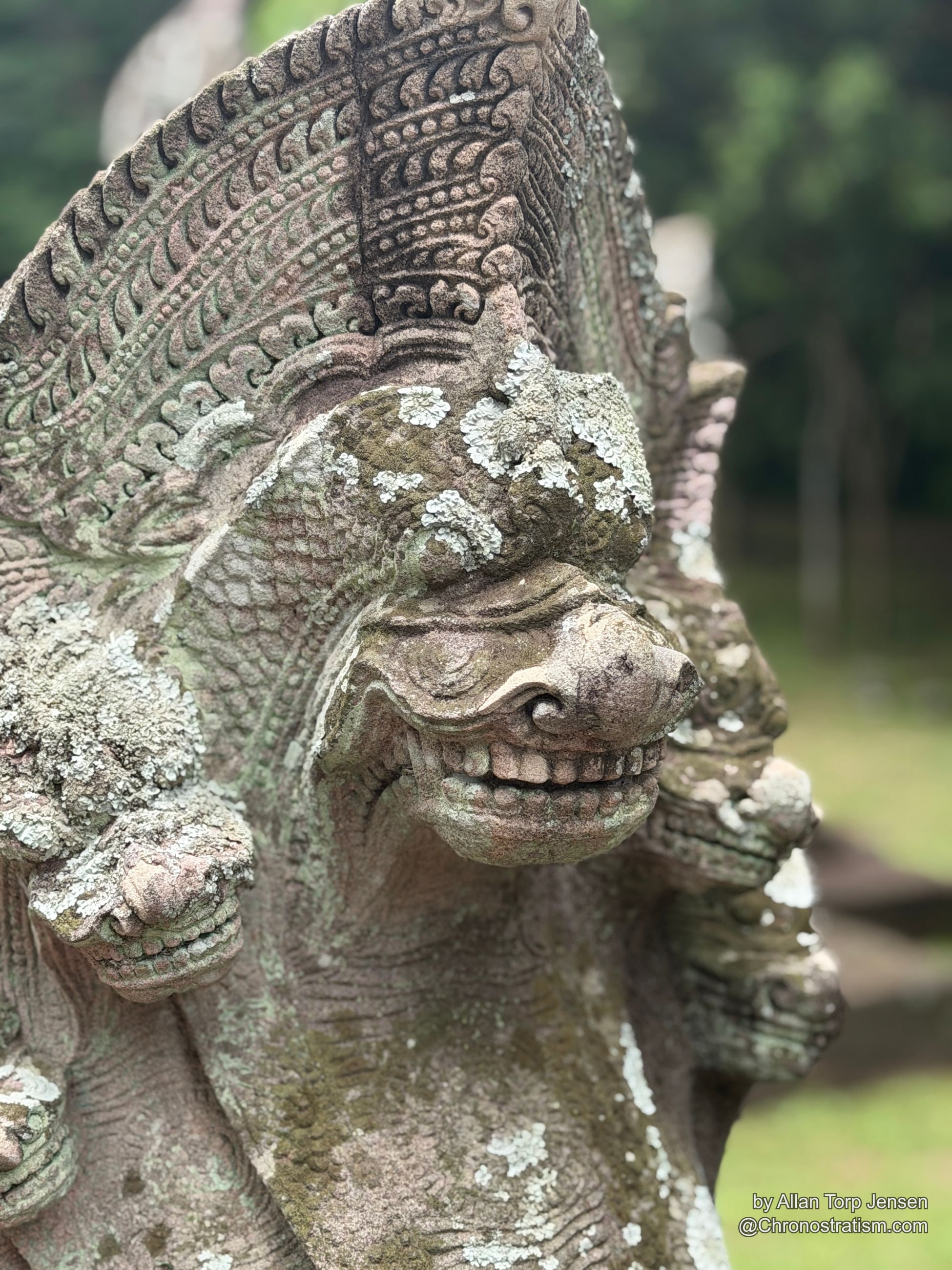 A close view of the guardian's carved features, weathered stone beneath lichen.
