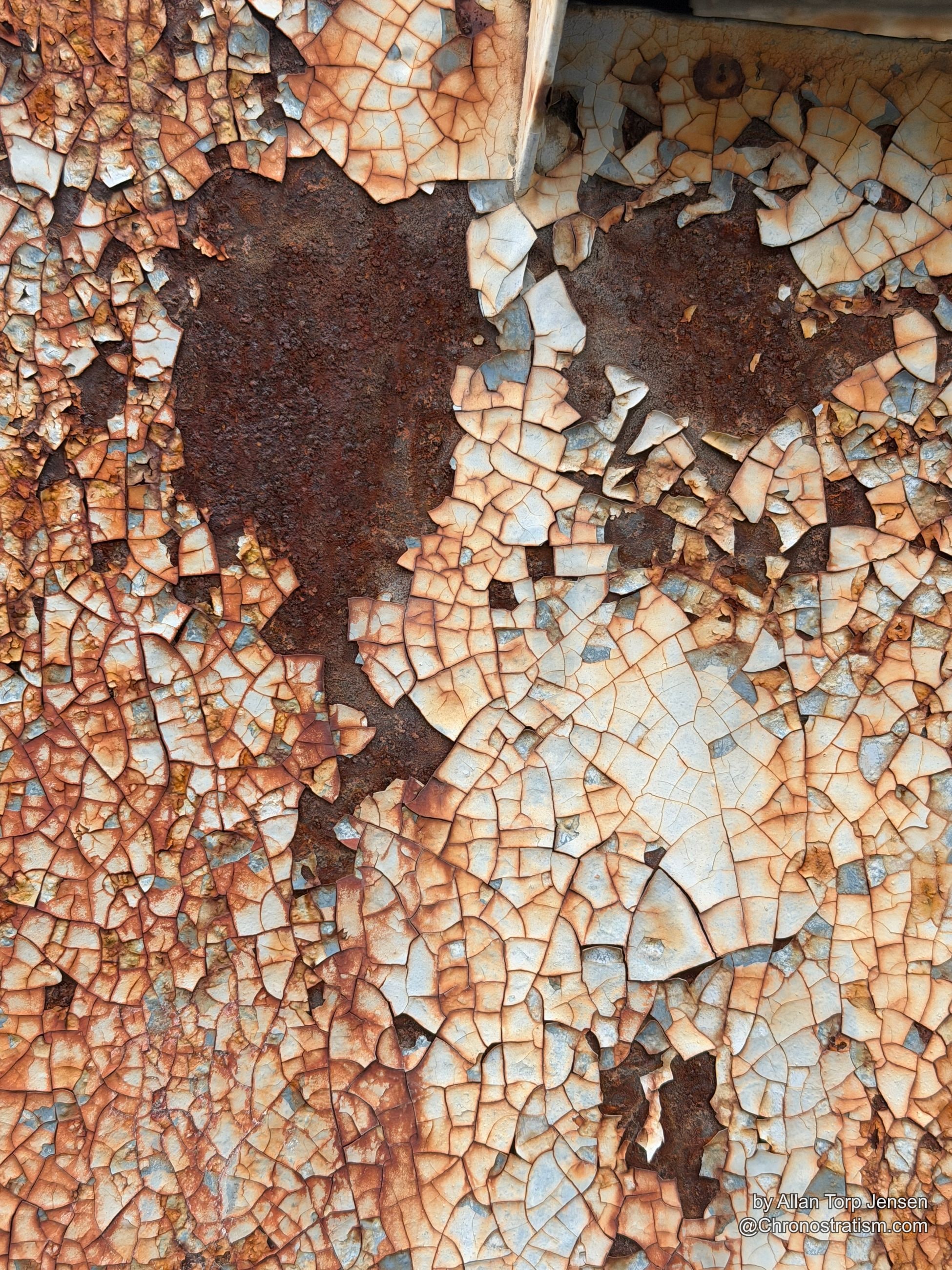 Craquelured paint gives way to bare rusted metal in patches, a wooden edge visible along one side of the panel.