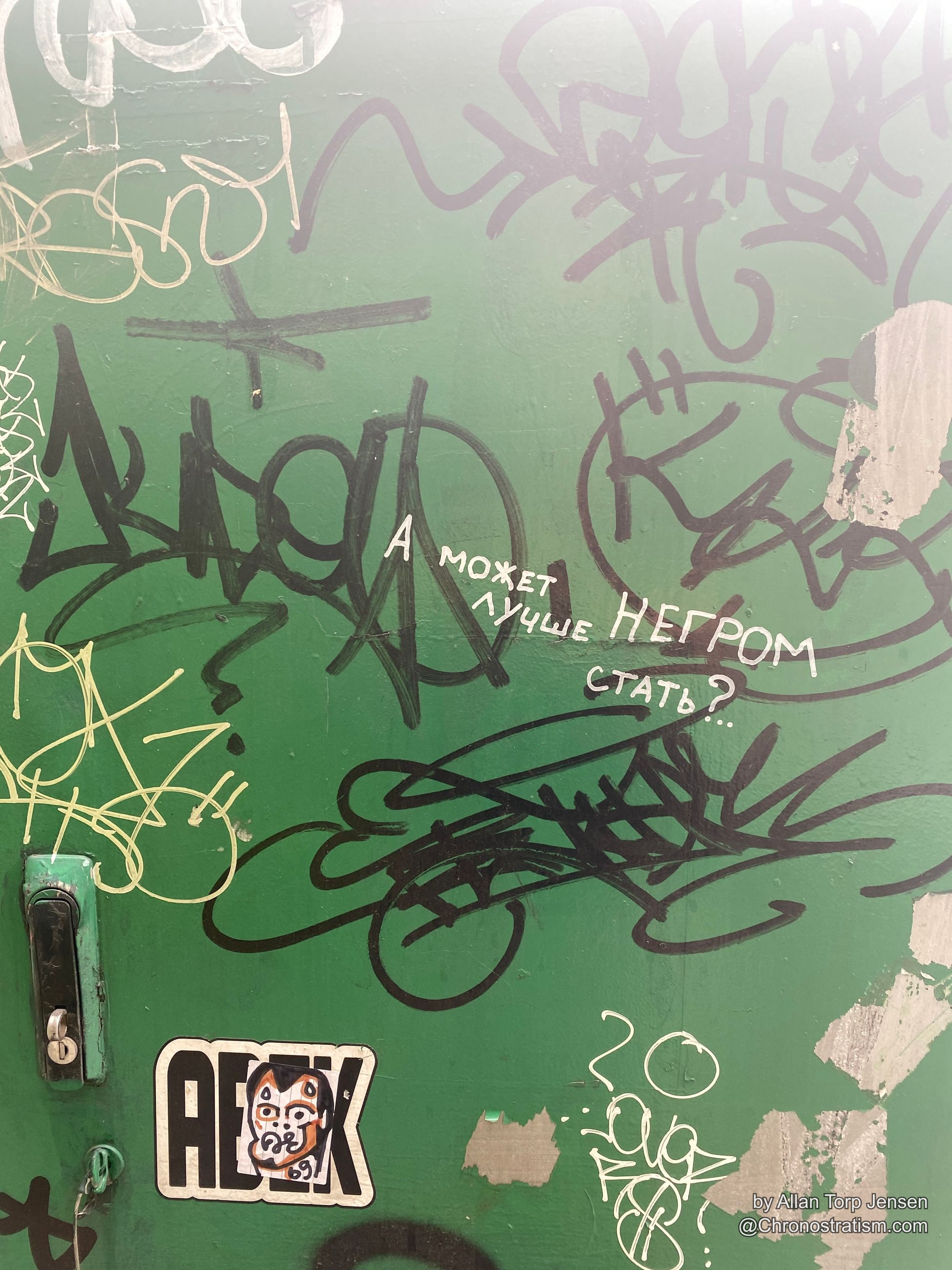 Cyrillic graffiti text and tag scribbles cover a weathered green door.
