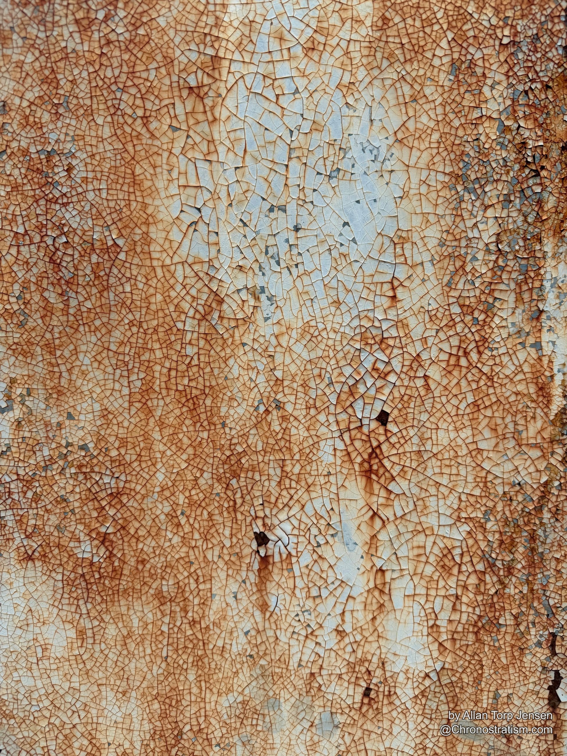 Dense micro-craquelure cracks a cream-painted metal surface, rust bleeding faintly through the web of hairline breaks.