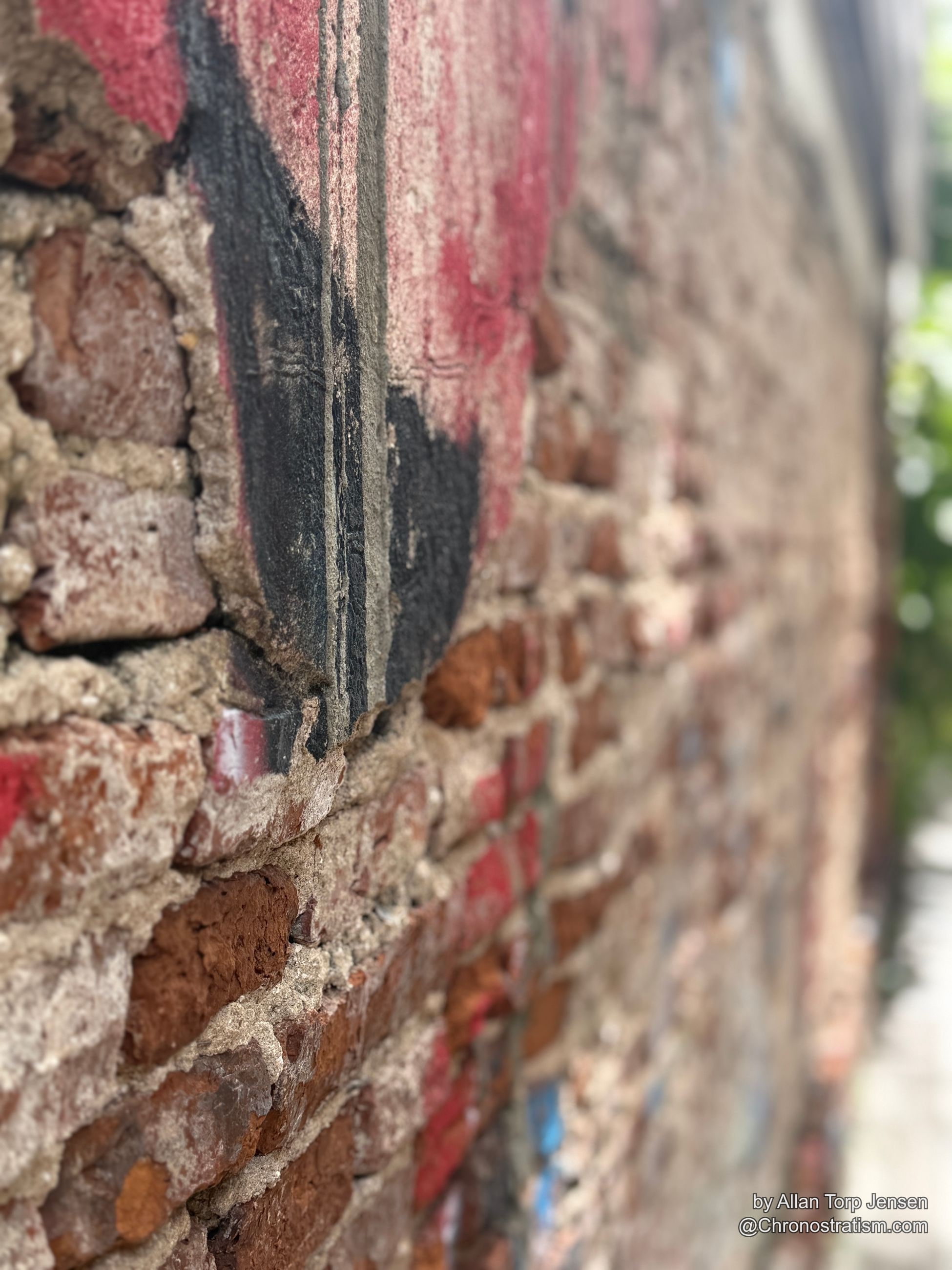 Faded mural paint meets bare brick at the wall's crumbling edge.