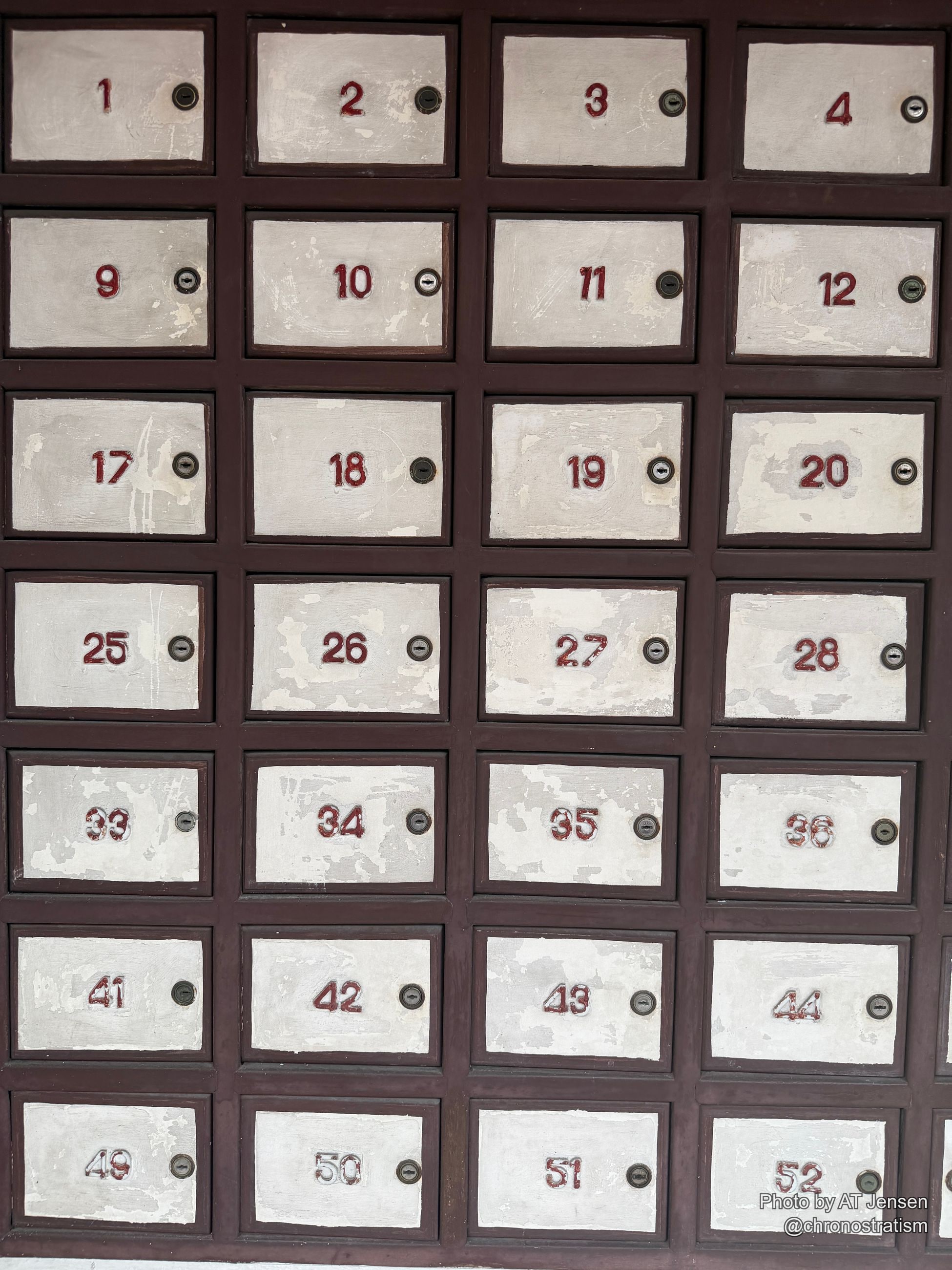 Hand-painted numbers mark a grid of worn, paint-chipped mailbox doors.