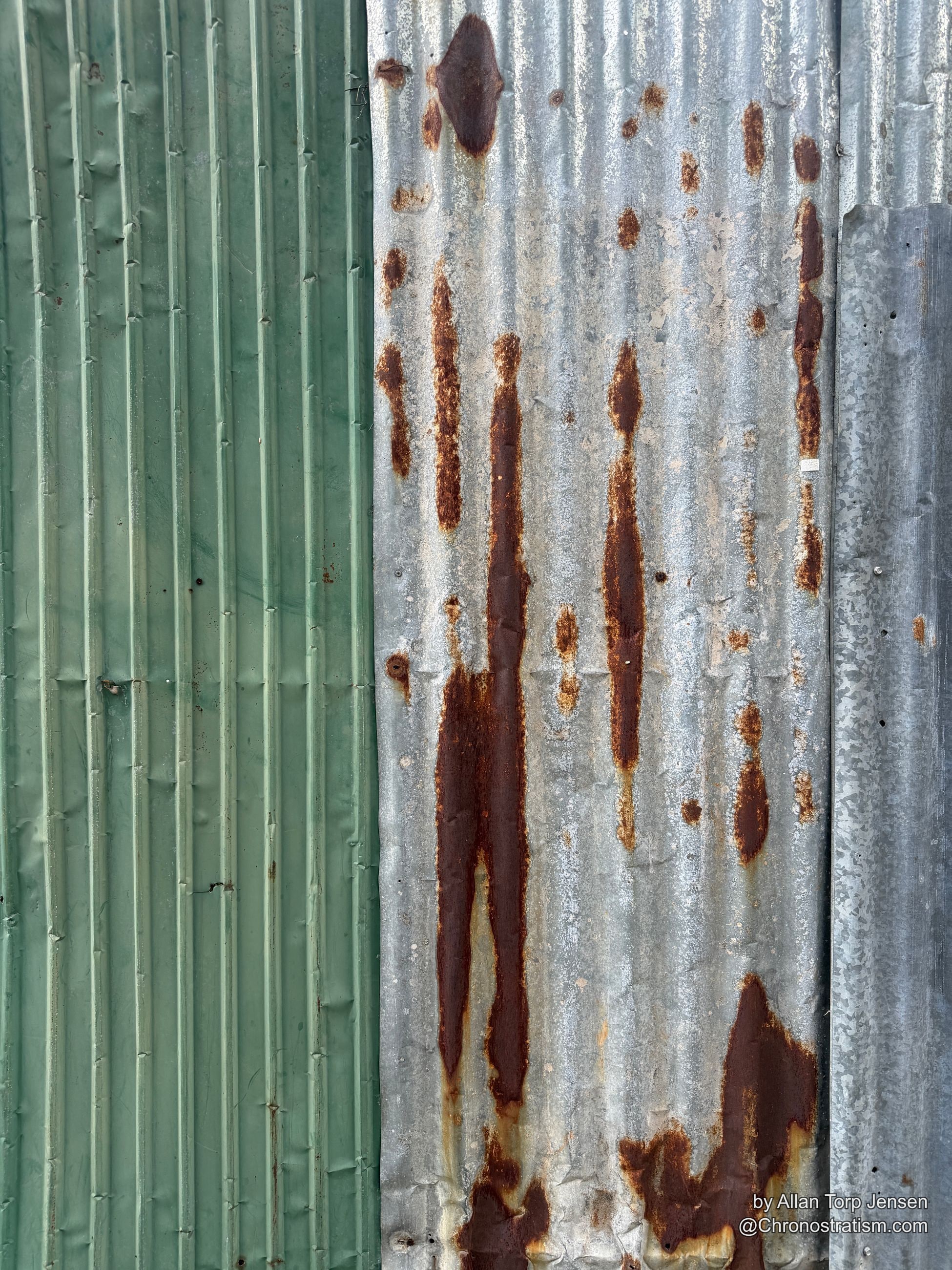 A heavily rusted galvanized panel meets a mint-green painted section below.