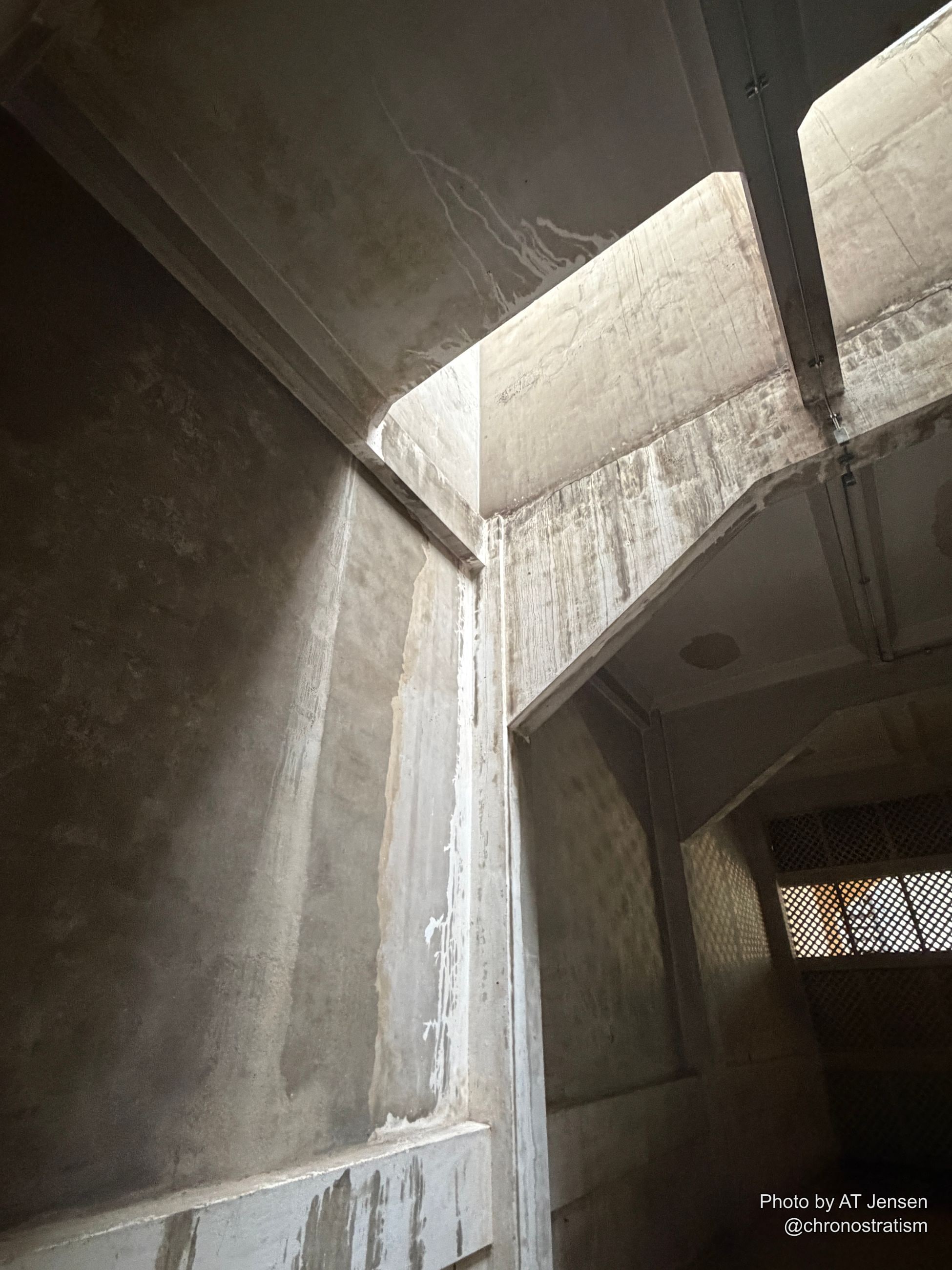Concrete beams meet in a dramatic interior corner, deep shadow cutting across the weathered surface.