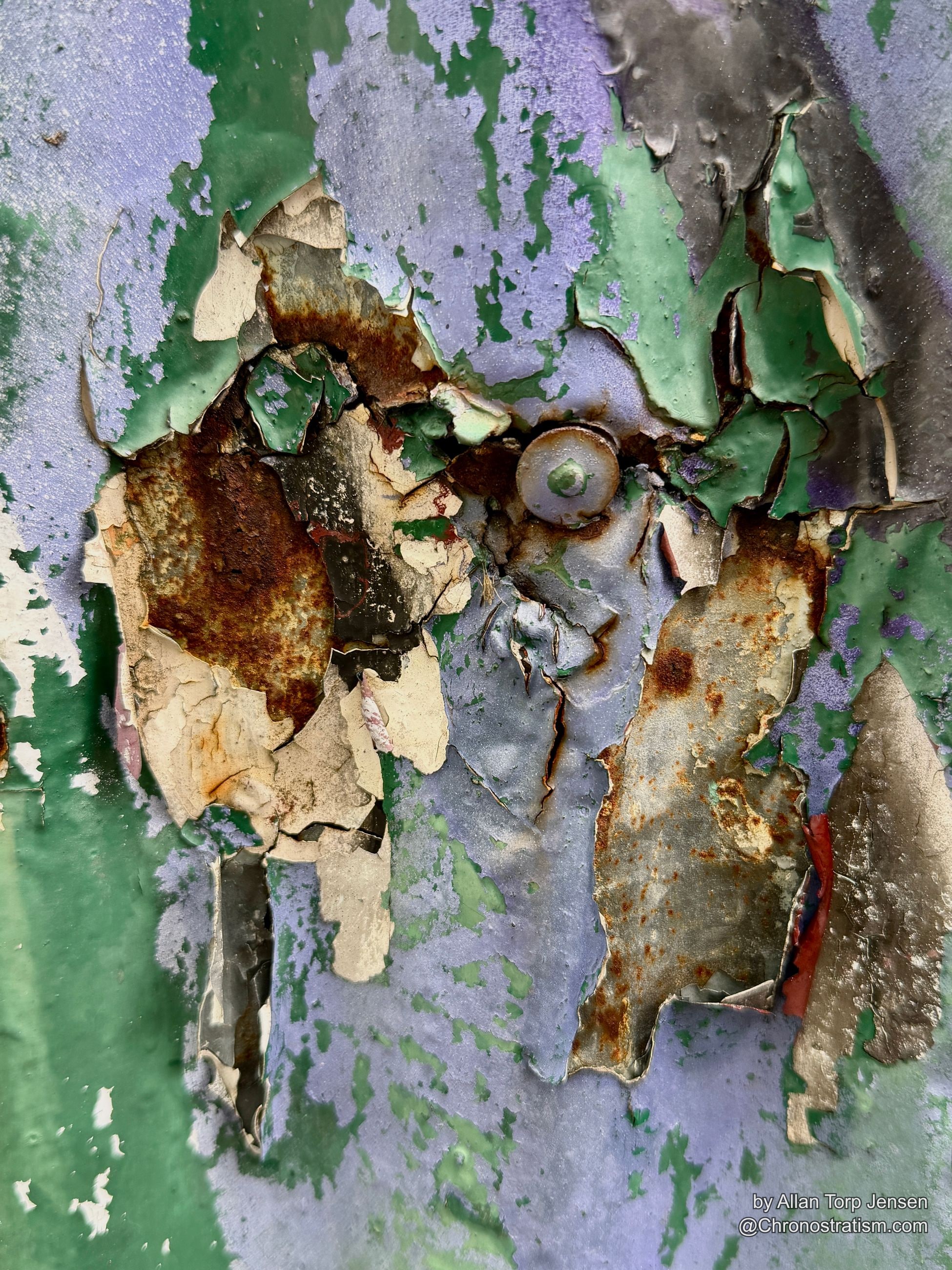 A large rust-eaten hole exposes bare metal beneath flaking green and purple paint.