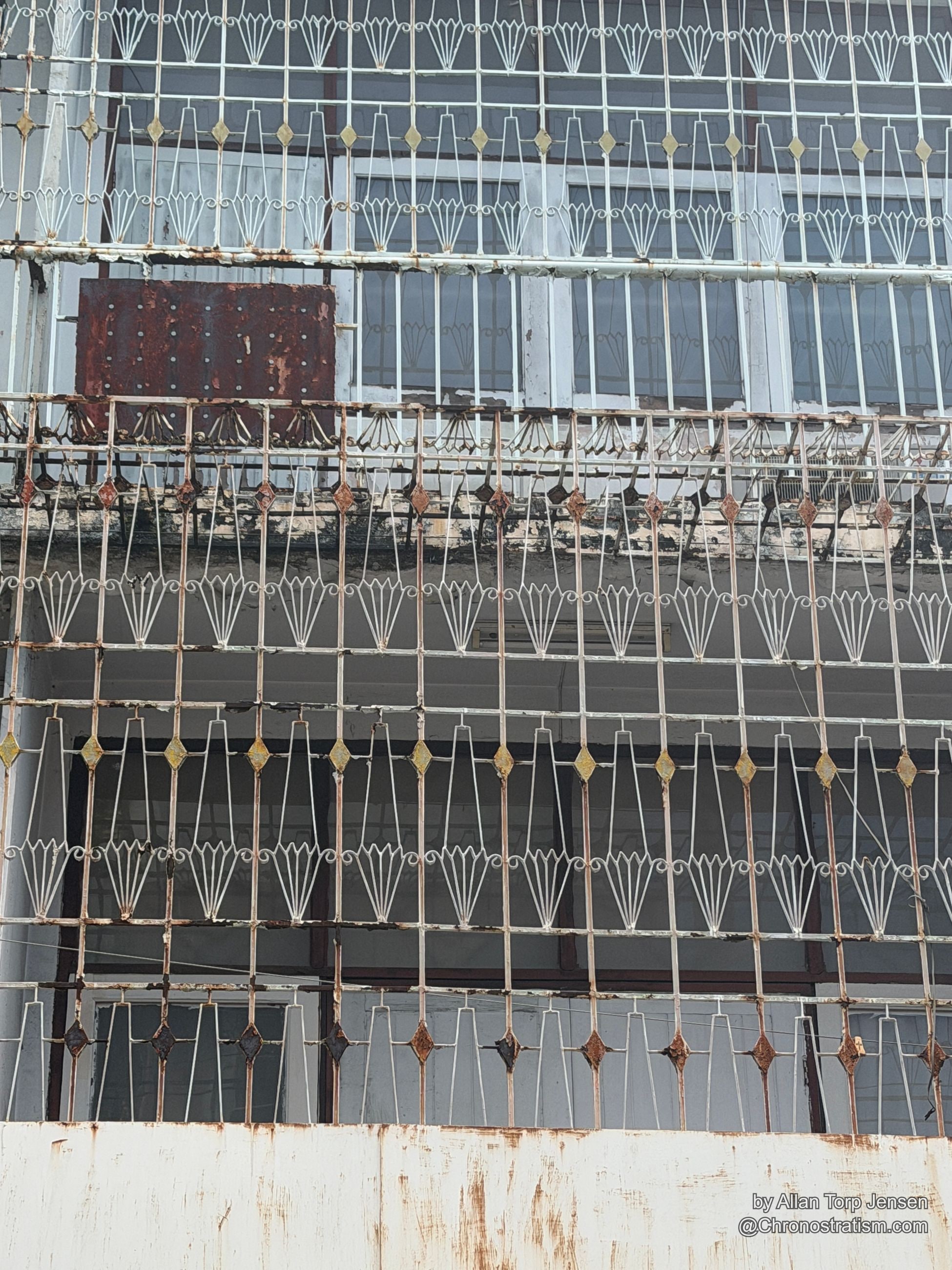 An ornate wrought-iron window grille shows rust spotting across its decorative scrollwork.
