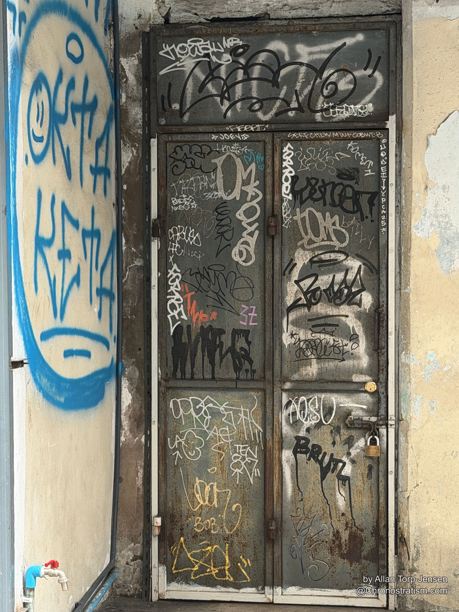 Overlapping graffiti tags cover a row of corrugated garage shutters.