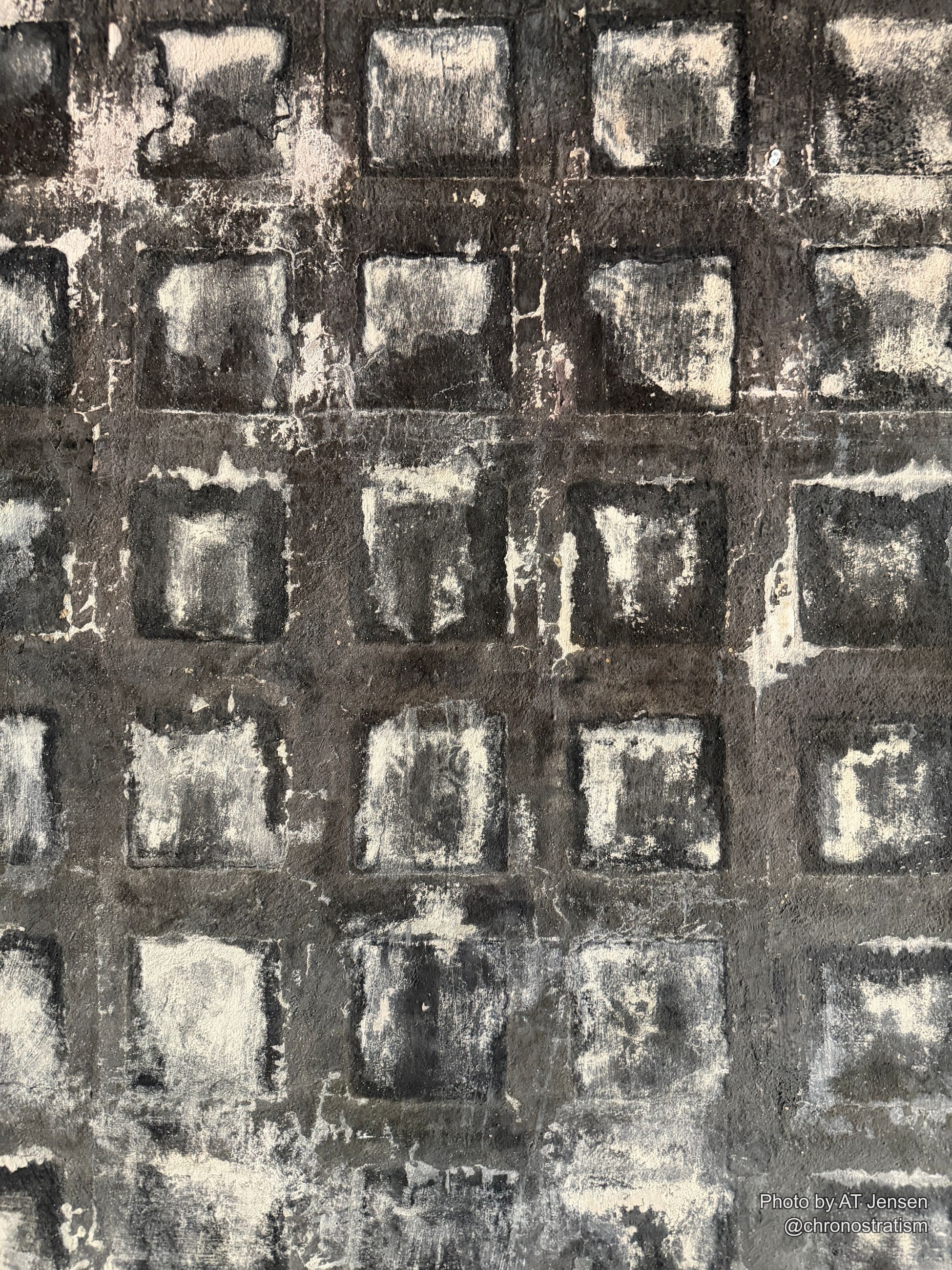 A hand-painted grid pattern stains unevenly, grime pooling darker within each square.