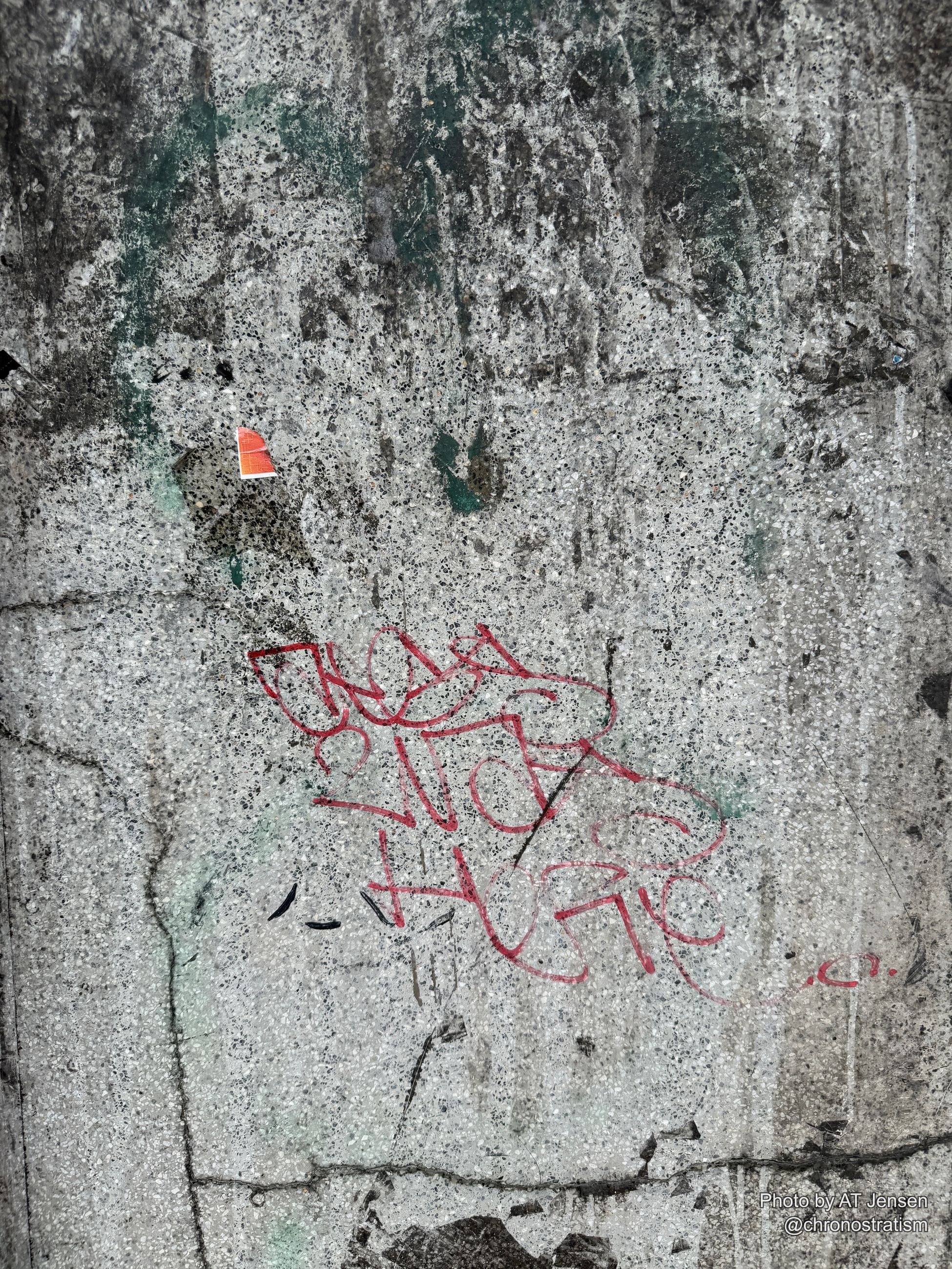 A looping red spray-painted tag marks a speckled terrazzo concrete surface.
