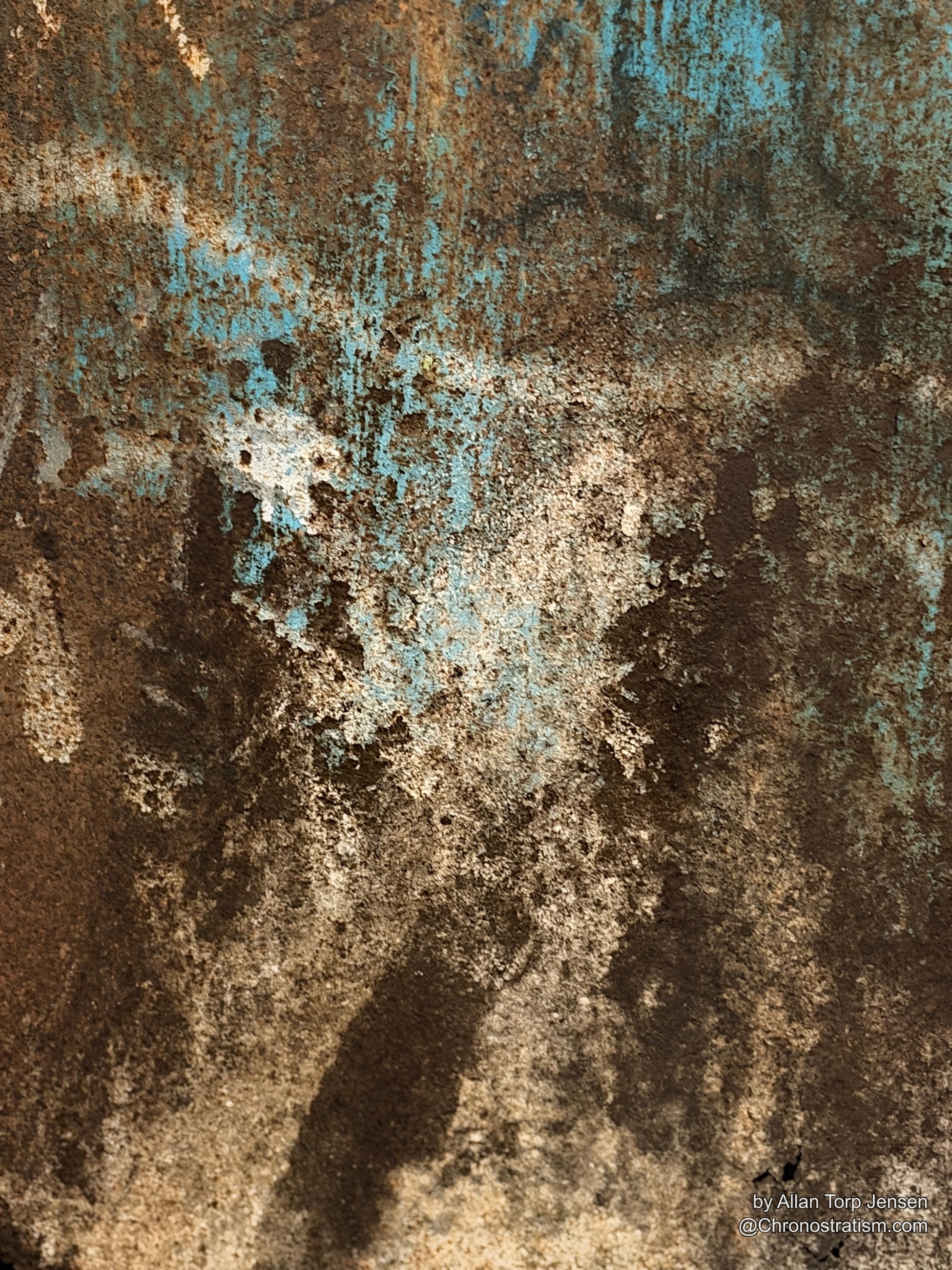 Rust bleeds heavily downward through a coat of blue paint.