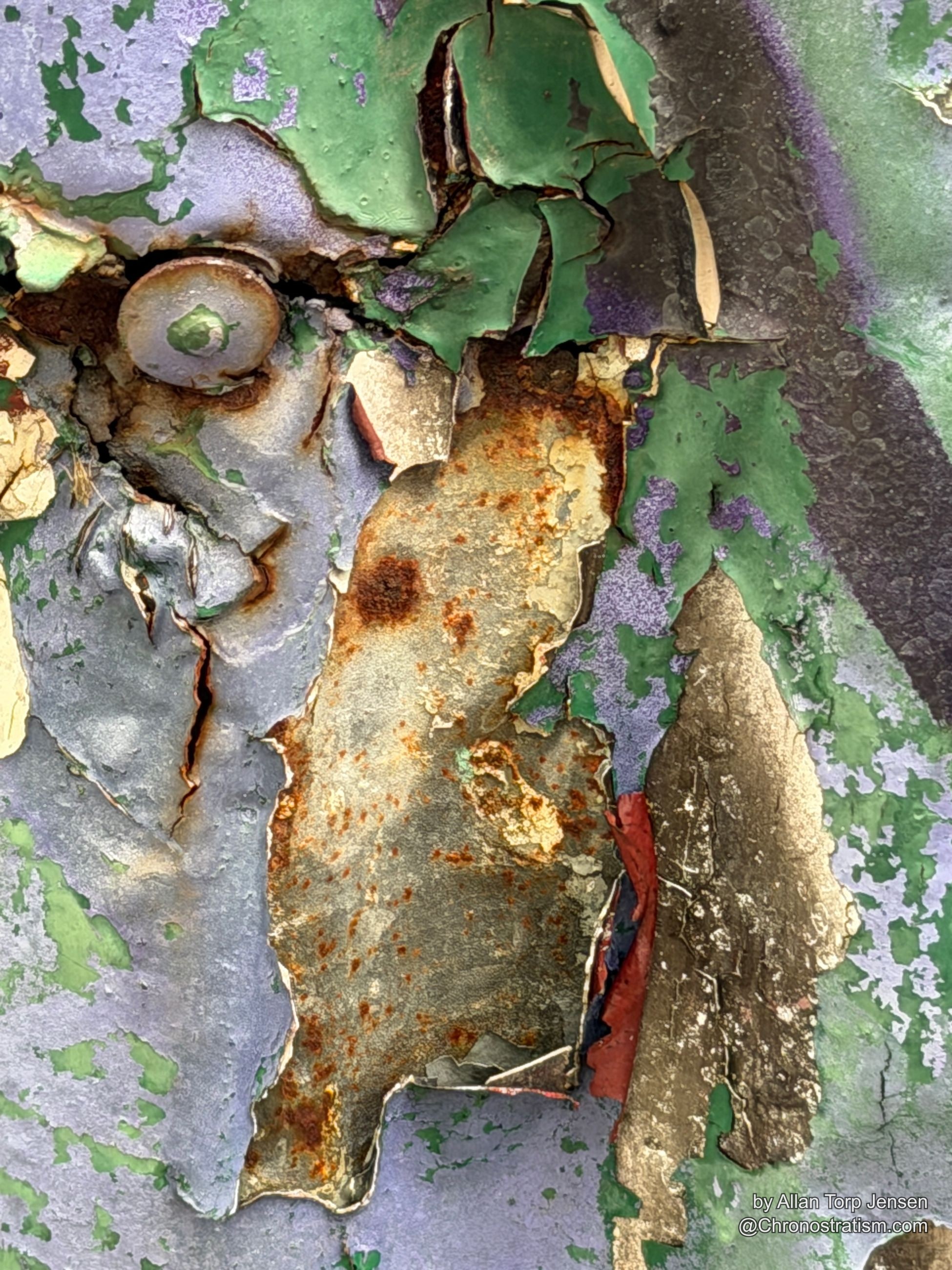 The same crack widens toward a second rivet streaked with rust.