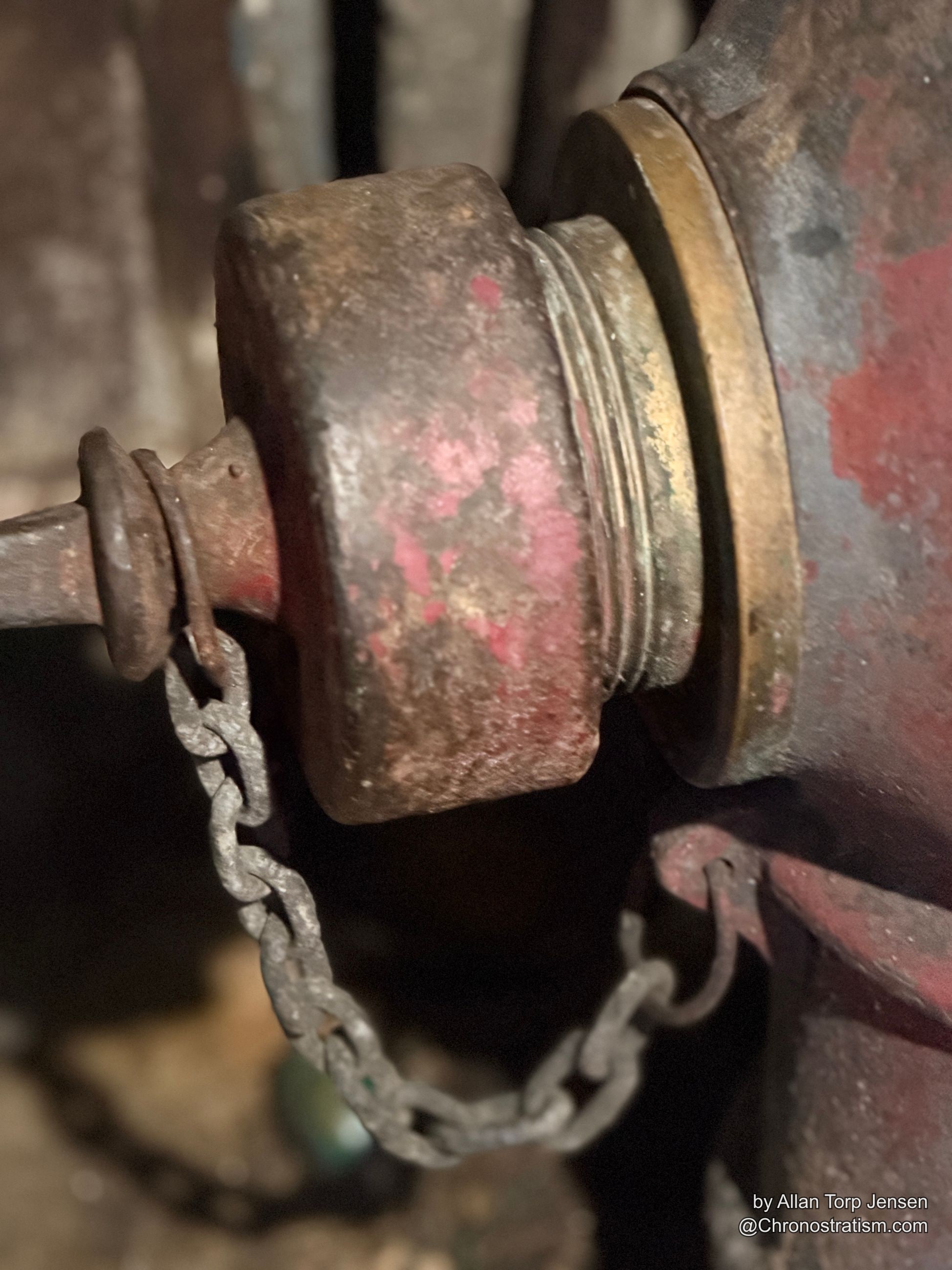 A second angle on the same rust-eaten hydrant cap, brass showing through worn paint.