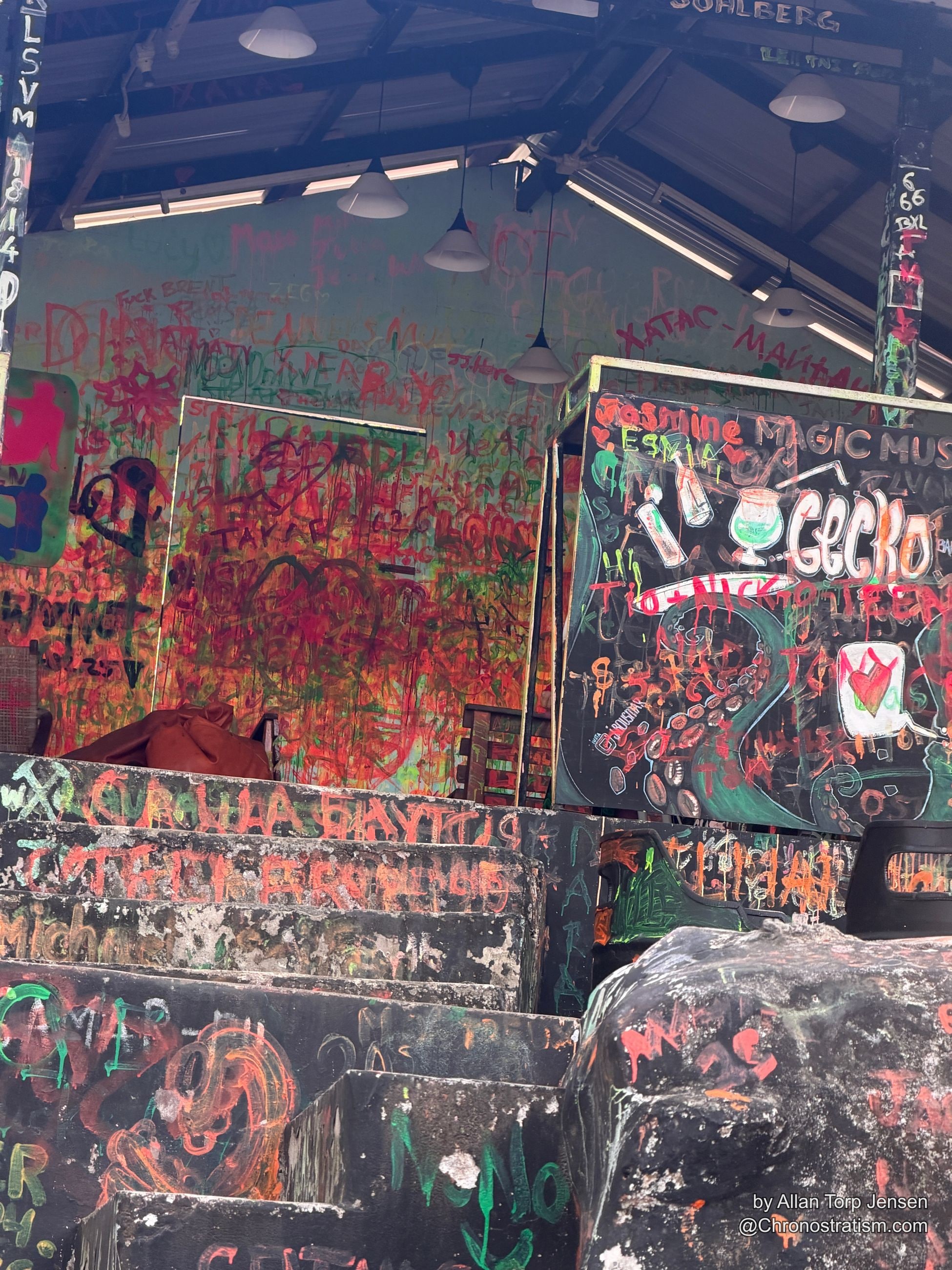 A stairwell interior is covered floor to ceiling in colorful graffiti and hand-drawn scrawl.