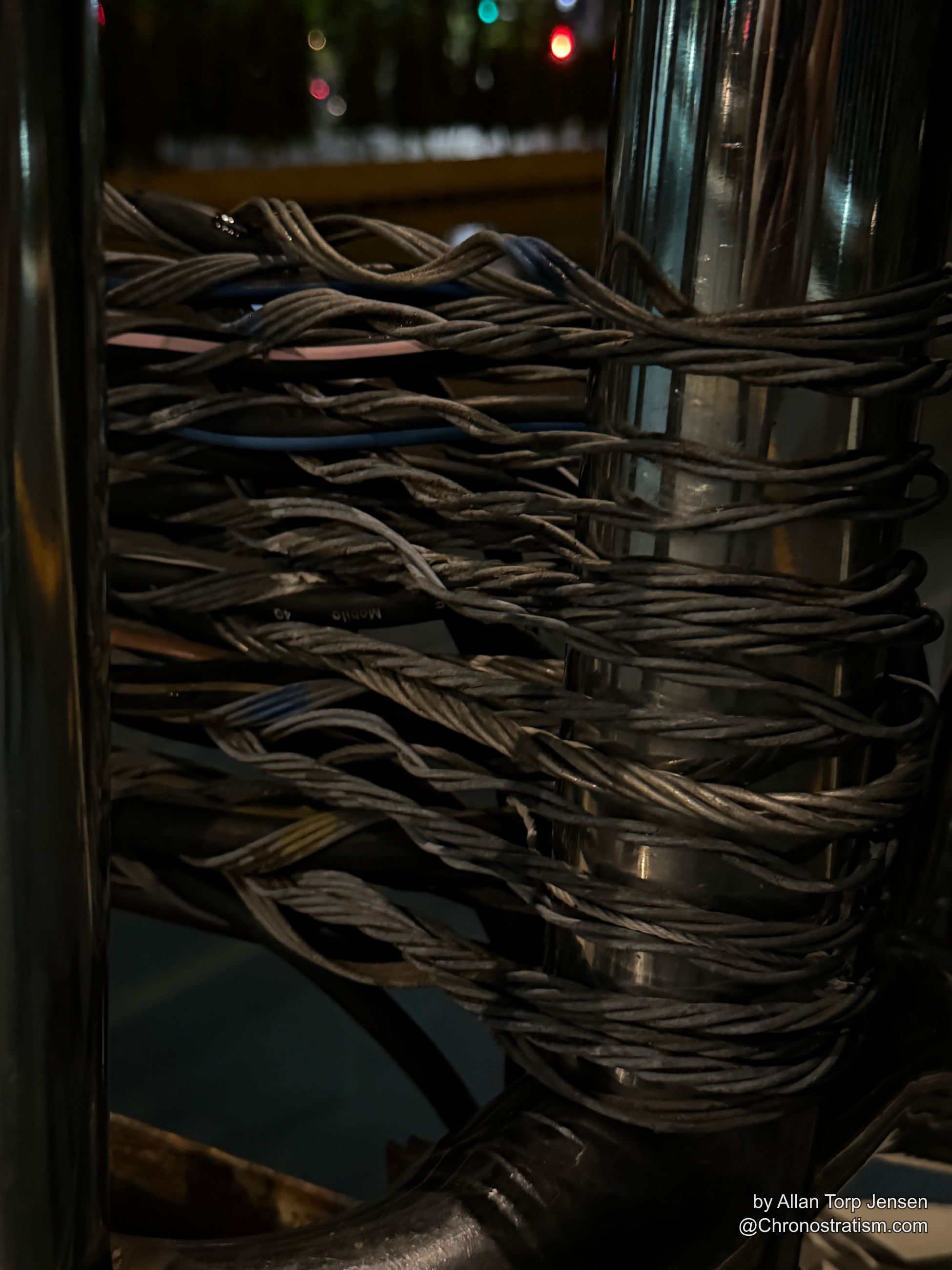 A stencilled marker sits beside a knot of aging telecom cable.