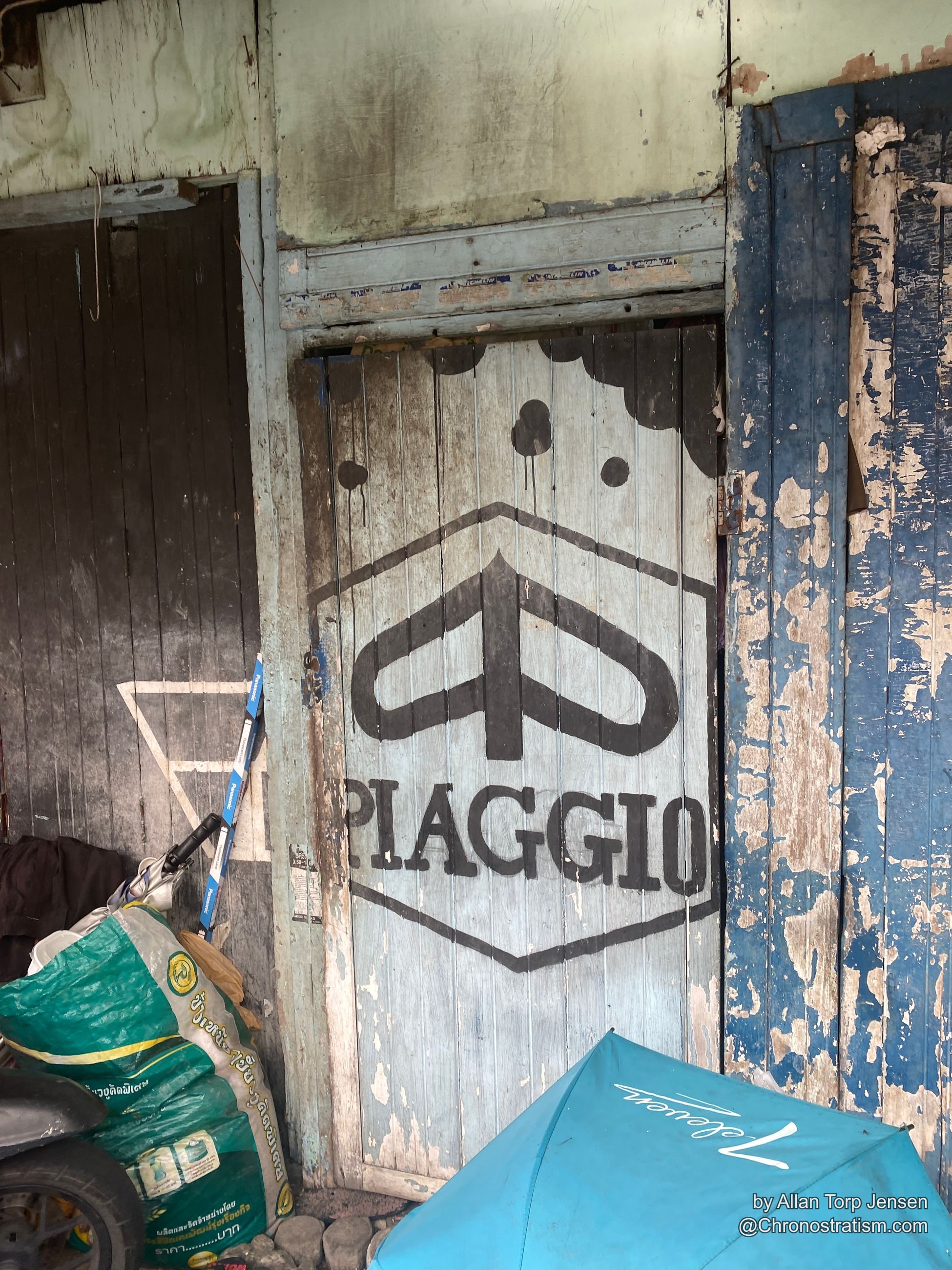 The stencilled Piaggio sign fades beneath heavily peeling layers of paint.