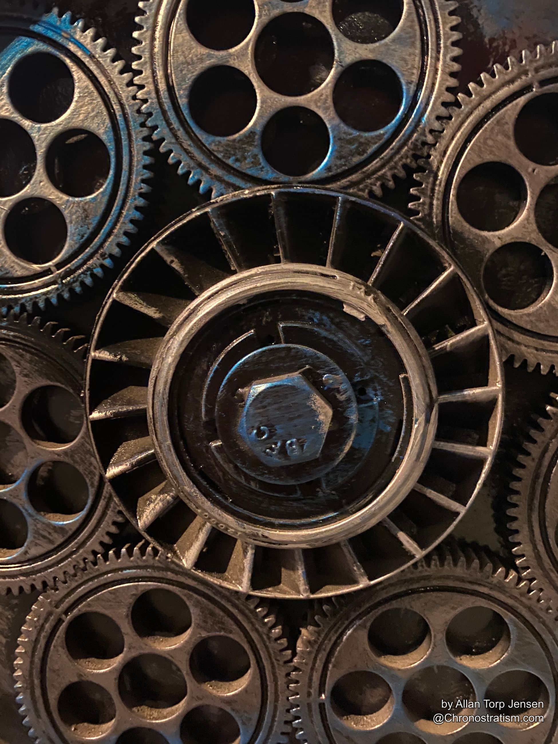 Toothed gears and bolt heads in dark, oxidized cast metal.