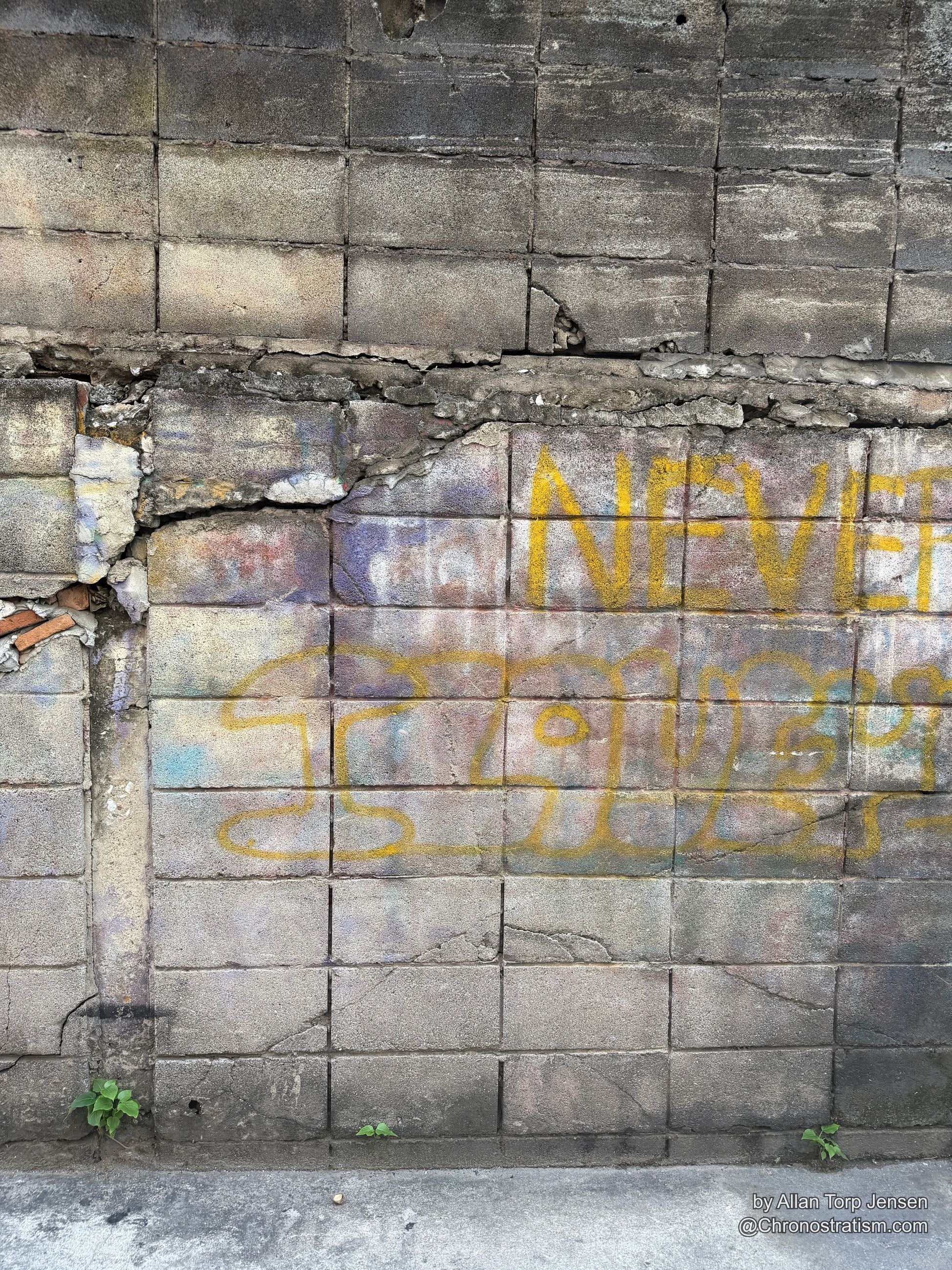 Vivid yellow spray-paint graffiti letters sprawl across a cracked tiled wall.