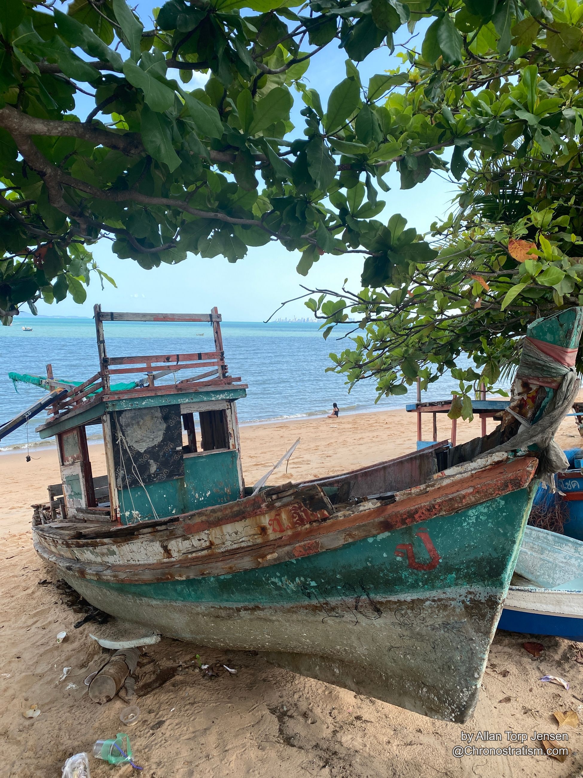 A weathered wooden boat hull with peeling teal paint and heavy rust staining along its seams.