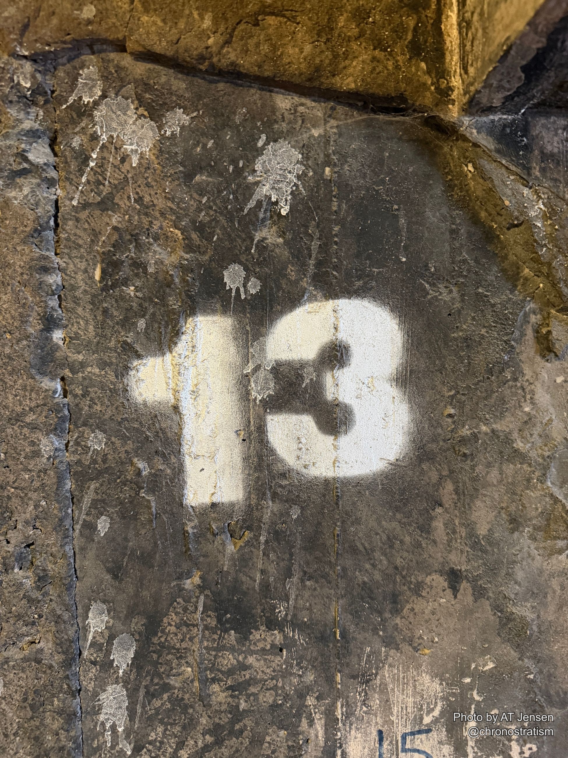 A white stencilled symbol marks a dark, grimy stone wall.
